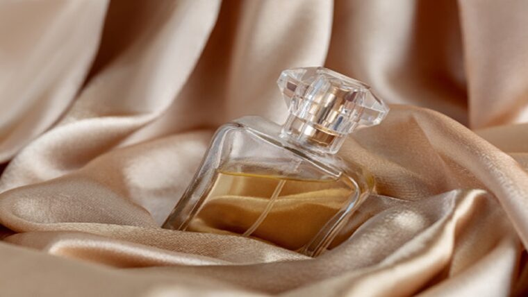 glass bottle of perfume on golden silk background.