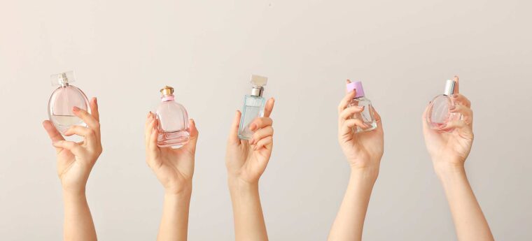 Five hands holding a unlabeled perfumes